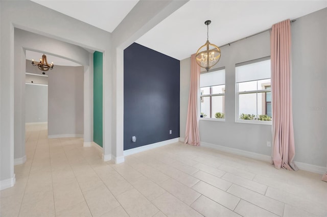 unfurnished room with a chandelier, light tile patterned floors, and baseboards