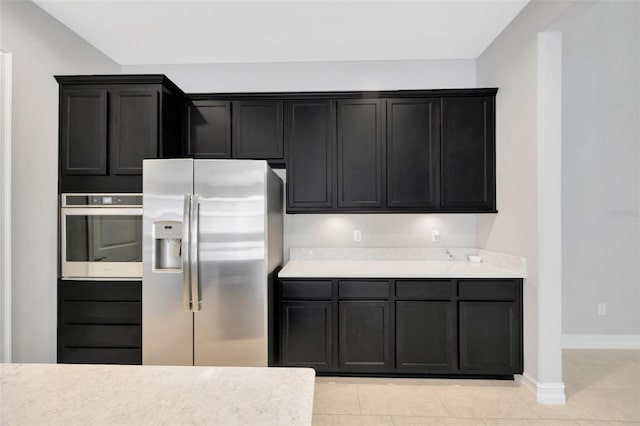 kitchen with appliances with stainless steel finishes, baseboards, dark cabinetry, and light countertops