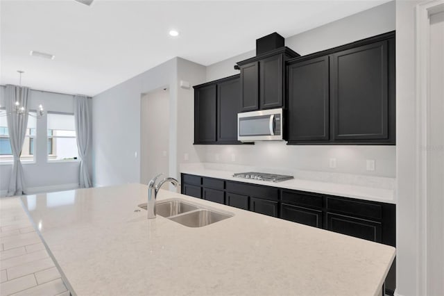 kitchen featuring a sink, appliances with stainless steel finishes, a center island with sink, dark cabinetry, and recessed lighting