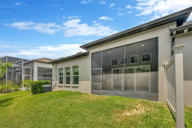 rear view of property featuring stucco siding and a yard