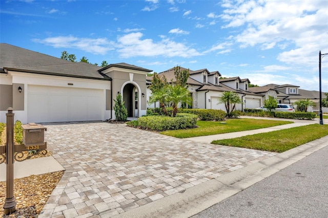 view of front of home featuring a garage, stucco siding, decorative driveway, a residential view, and a front lawn