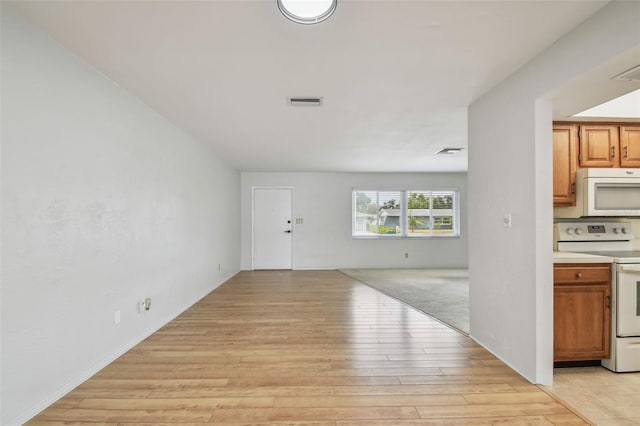11762 82nd Ter, Seminole, FL 33772 - kitchen with white appliances, light wood-style flooring, open floor plan, light countertops, and brown cabinetry