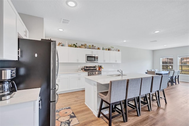 12710 Hysmith Loop, Parrish, FL 34219 - kitchen with stainless steel appliances, a breakfast bar, light wood-style floors, a sink, and white cabinetry