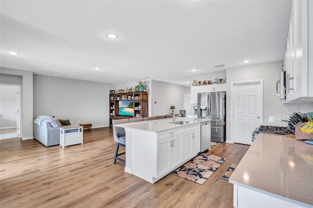 12710 Hysmith Loop, Parrish, FL 34219 - kitchen with appliances with stainless steel finishes, open floor plan, light wood-style flooring, a sink, and a kitchen breakfast bar
