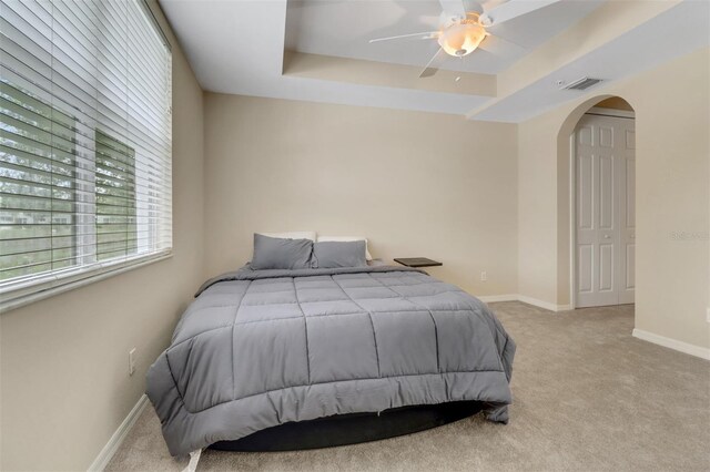 1330 Mariposa Cir Unit 104, Naples, FL 34105 - bedroom featuring carpet, arched walkways, a tray ceiling, and a ceiling fan
