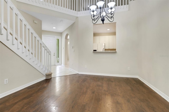 1330 Mariposa Cir Unit 104, Naples, FL 34105 - entryway featuring stairway, hardwood / wood-style flooring, arched walkways, a chandelier, and a towering ceiling