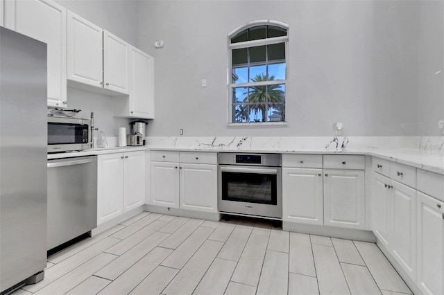 1330 Mariposa Cir Unit 104, Naples, FL 34105 - kitchen featuring stainless steel appliances, white cabinetry, and light stone countertops
