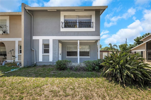 2048 Los Lomas Dr, Clearwater, FL 33763 - view of property with stucco siding, a front lawn, and a balcony