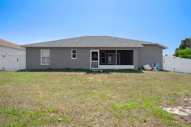 rear view of house featuring a gate, a sunroom, stucco siding, and roof with shingles