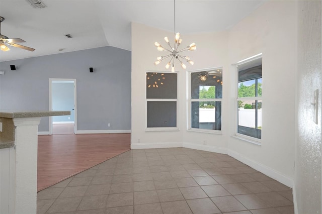 unfurnished dining area featuring lofted ceiling, a ceiling fan, a chandelier, baseboards, and light tile patterned floors