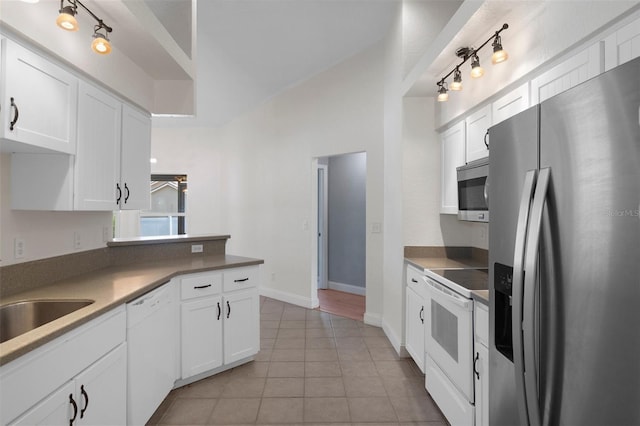 kitchen with stainless steel appliances, white cabinetry, light tile patterned flooring, a peninsula, and baseboards
