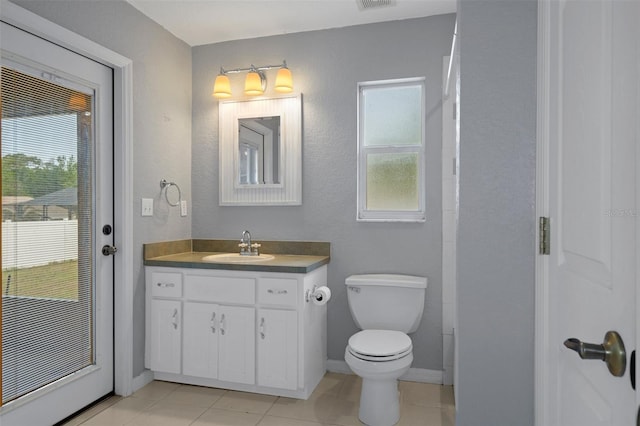 bathroom with toilet, tile patterned flooring, vanity, and baseboards