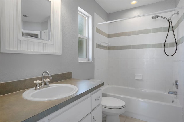 full bathroom featuring toilet, washtub / shower combination, vanity, and a textured wall