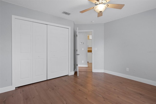 unfurnished bedroom featuring wood finished floors, a closet, baseboards, and ceiling fan