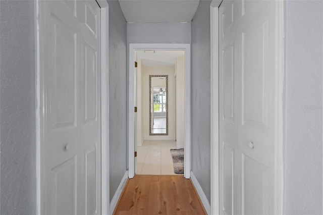 hall with baseboards and light wood-style flooring