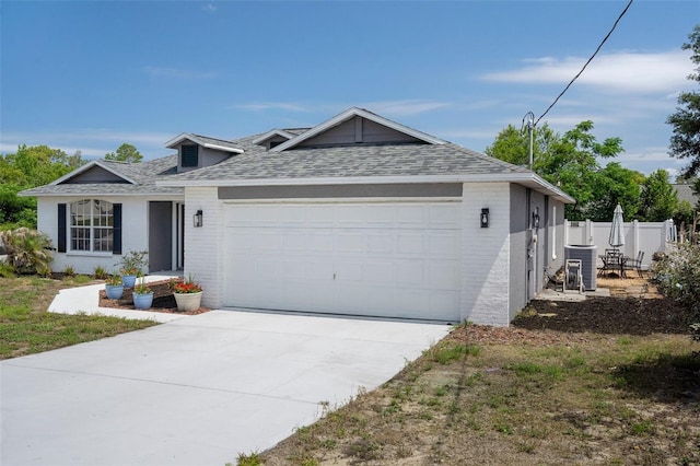 view of front facade with fence, brick siding, a garage, a shingled roof, and concrete driveway