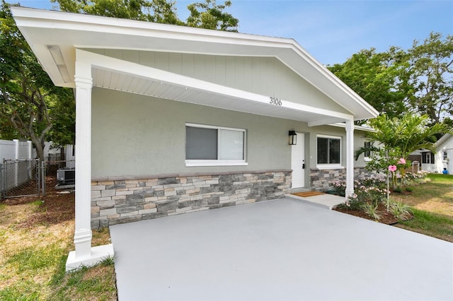 view of front of home with stone siding, fence, and a patio area
