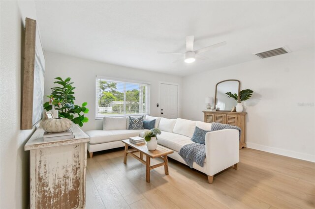living room with light wood finished floors, a ceiling fan, and baseboards
