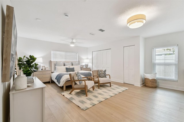 bedroom featuring multiple closets, light wood finished floors, and baseboards
