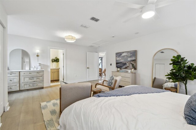 bedroom with light wood finished floors, connected bathroom, and attic access
