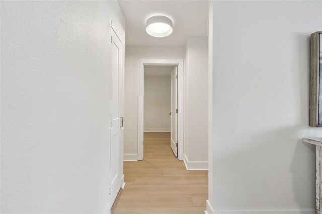 hall featuring light wood-type flooring and baseboards