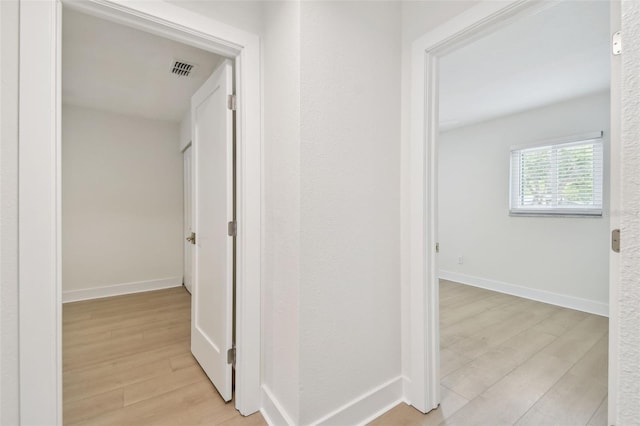 hall with light wood-style floors and baseboards