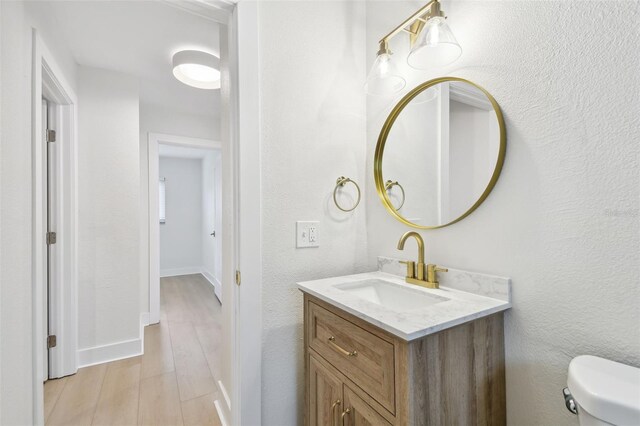bathroom featuring vanity, toilet, wood finished floors, and baseboards
