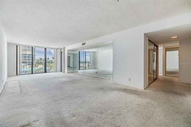 spare room with floor to ceiling windows, carpet flooring, and a textured ceiling