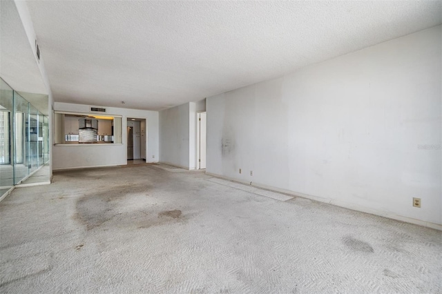 unfurnished living room featuring carpet floors, a textured ceiling, and baseboards