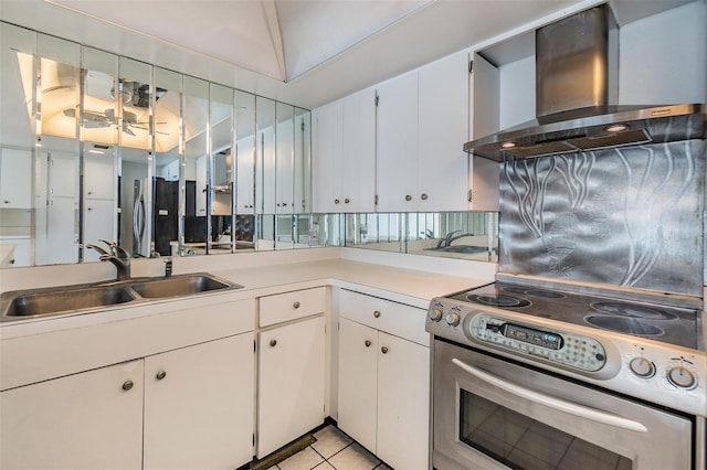 kitchen featuring wall chimney range hood, a sink, stainless steel appliances, and light countertops