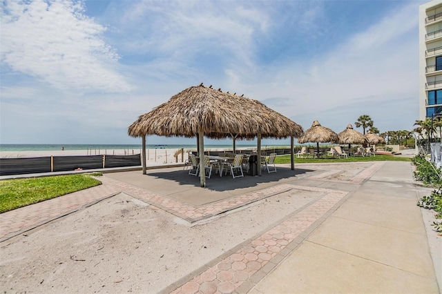 view of home's community featuring a patio and view of water and beach