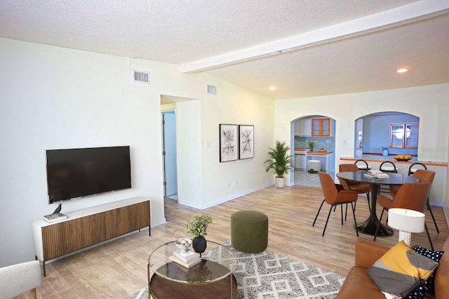 1111 Briarwood Rd, Brandon, FL 33511 - living area with light wood finished floors, baseboards, arched walkways, and a textured ceiling