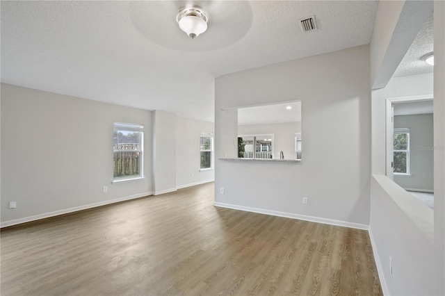 unfurnished living room with visible vents, wood finished floors, baseboards, and a healthy amount of sunlight