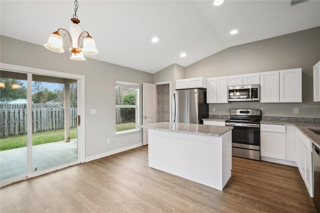 kitchen with stainless steel appliances, vaulted ceiling, a chandelier, a center island, and white cabinets