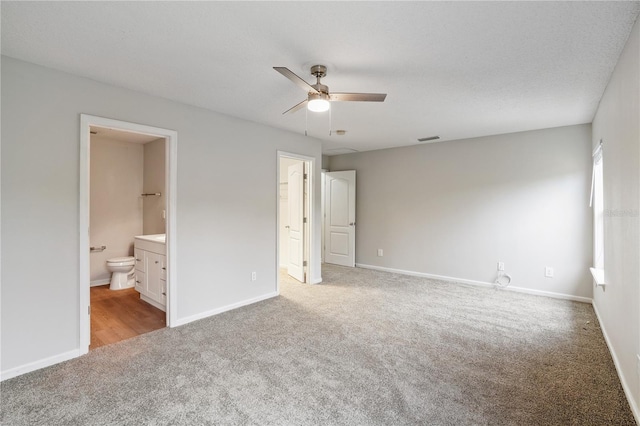 unfurnished bedroom featuring ensuite bathroom, carpet floors, baseboards, and visible vents