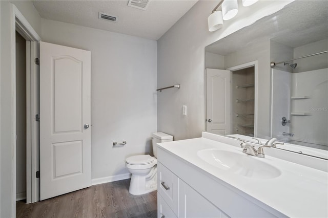 full bathroom featuring toilet, walk in shower, visible vents, vanity, and wood finished floors