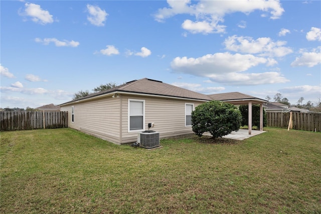 rear view of property featuring central AC unit, a yard, a patio, and a fenced backyard
