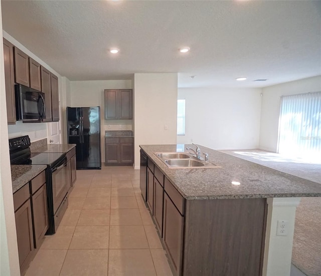 10928 Carlton Fields Dr, Riverview, FL 33579 - kitchen featuring light tile patterned floors, a wealth of natural light, a sink, black appliances, and a kitchen island with sink