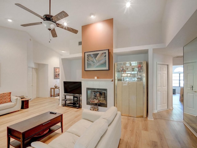 living room featuring light wood finished floors, ceiling fan, a fireplace, recessed lighting, and high vaulted ceiling