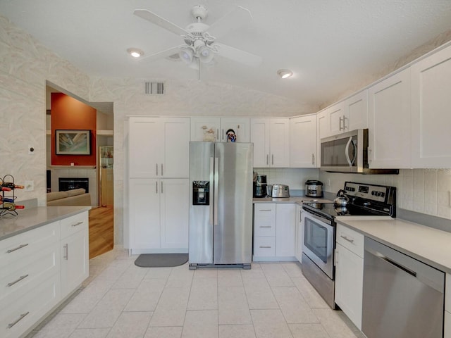 kitchen featuring stainless steel appliances, white cabinets, ceiling fan, light countertops, and vaulted ceiling