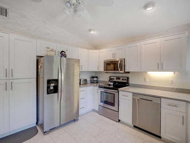 kitchen featuring appliances with stainless steel finishes, vaulted ceiling, light countertops, white cabinetry, and ceiling fan
