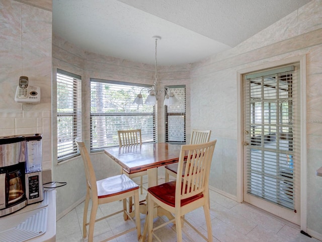 dining space with a textured ceiling, vaulted ceiling, baseboards, and tile patterned floors