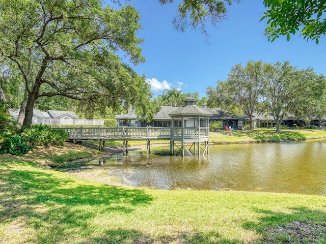 dock area featuring a gazebo, a water view, and a lawn