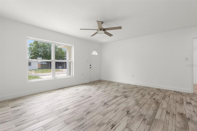 spare room featuring a ceiling fan, light wood-style floors, and baseboards