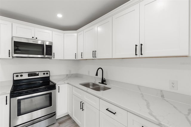 kitchen featuring appliances with stainless steel finishes, a sink, white cabinetry, and recessed lighting