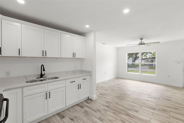 kitchen with a sink, white cabinetry, recessed lighting, ceiling fan, and baseboards