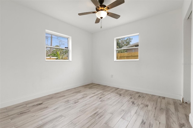 spare room with plenty of natural light, wood finished floors, baseboards, and ceiling fan
