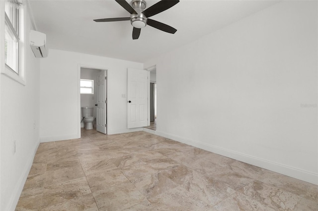 unfurnished bedroom with a wall mounted AC, baseboards, ensuite bathroom, and a ceiling fan