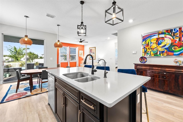 kitchen with a sink, light wood-style floors, light countertops, hanging light fixtures, and recessed lighting