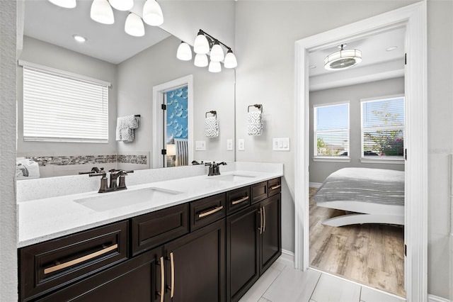 ensuite bathroom featuring double vanity and baseboards